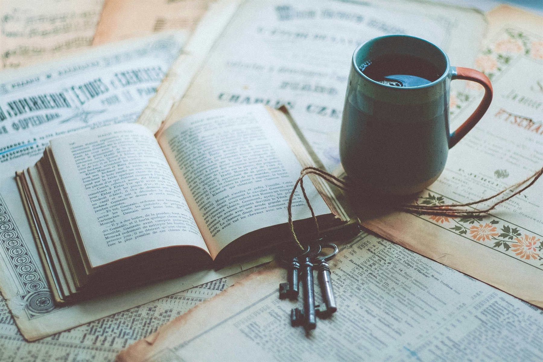 An open book, keys, and a warm mug arranged for quiet reflection